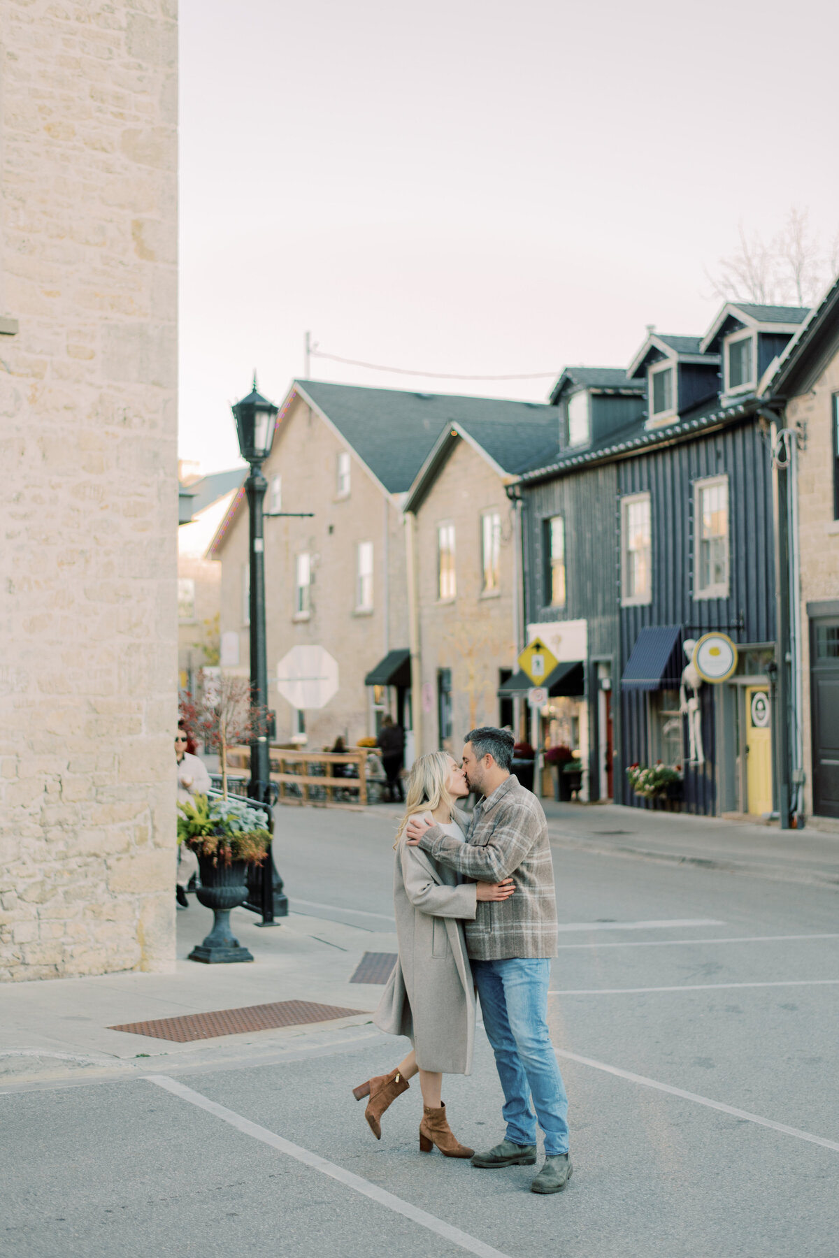 A joyful moment at Elora Mill, with a groom lifting his bride against the backdrop of the iconic stone walls and grand gates