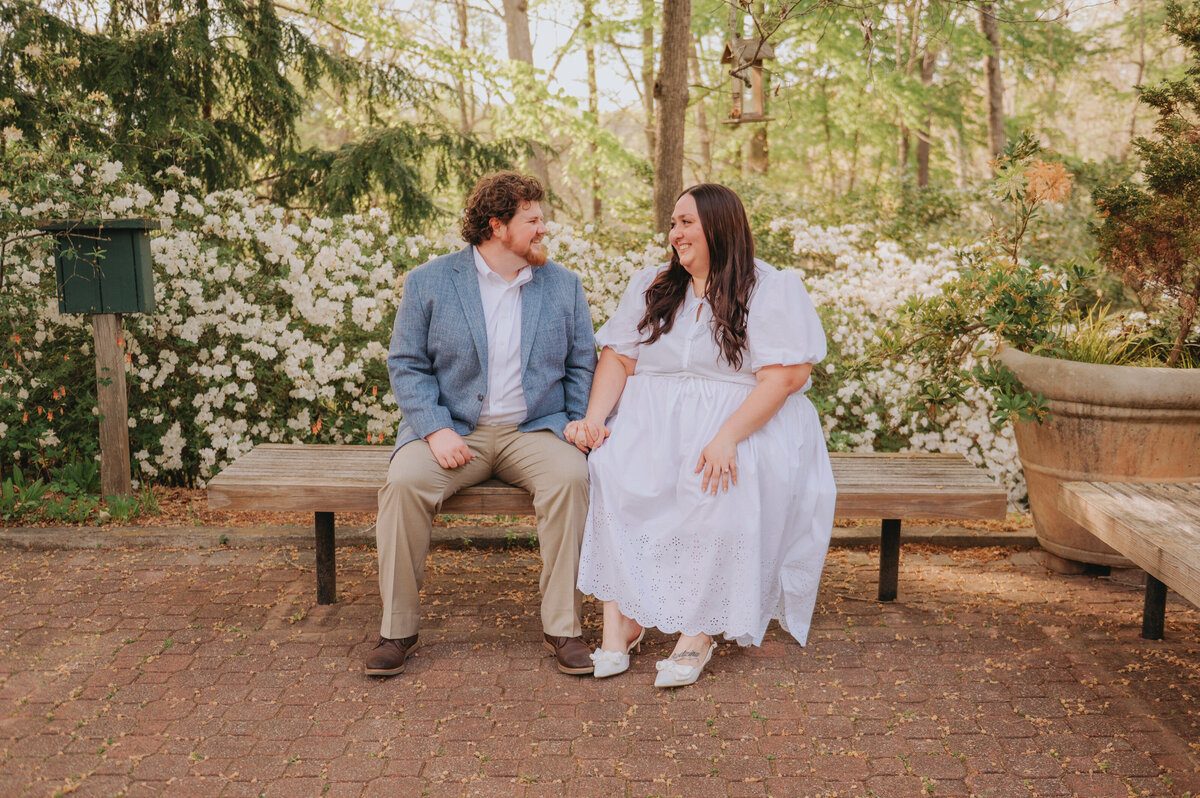 A couple holds hands while sitting on a bench