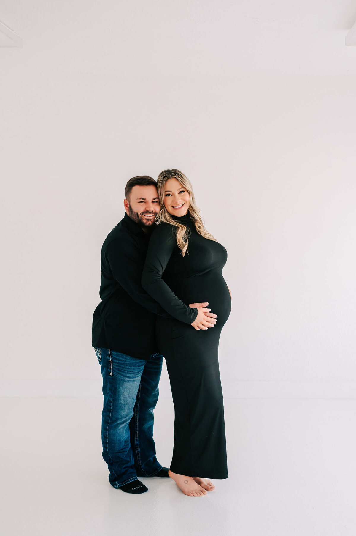 pregnant couple cuddling and smiling during maternity photography session in Joplin Missouri