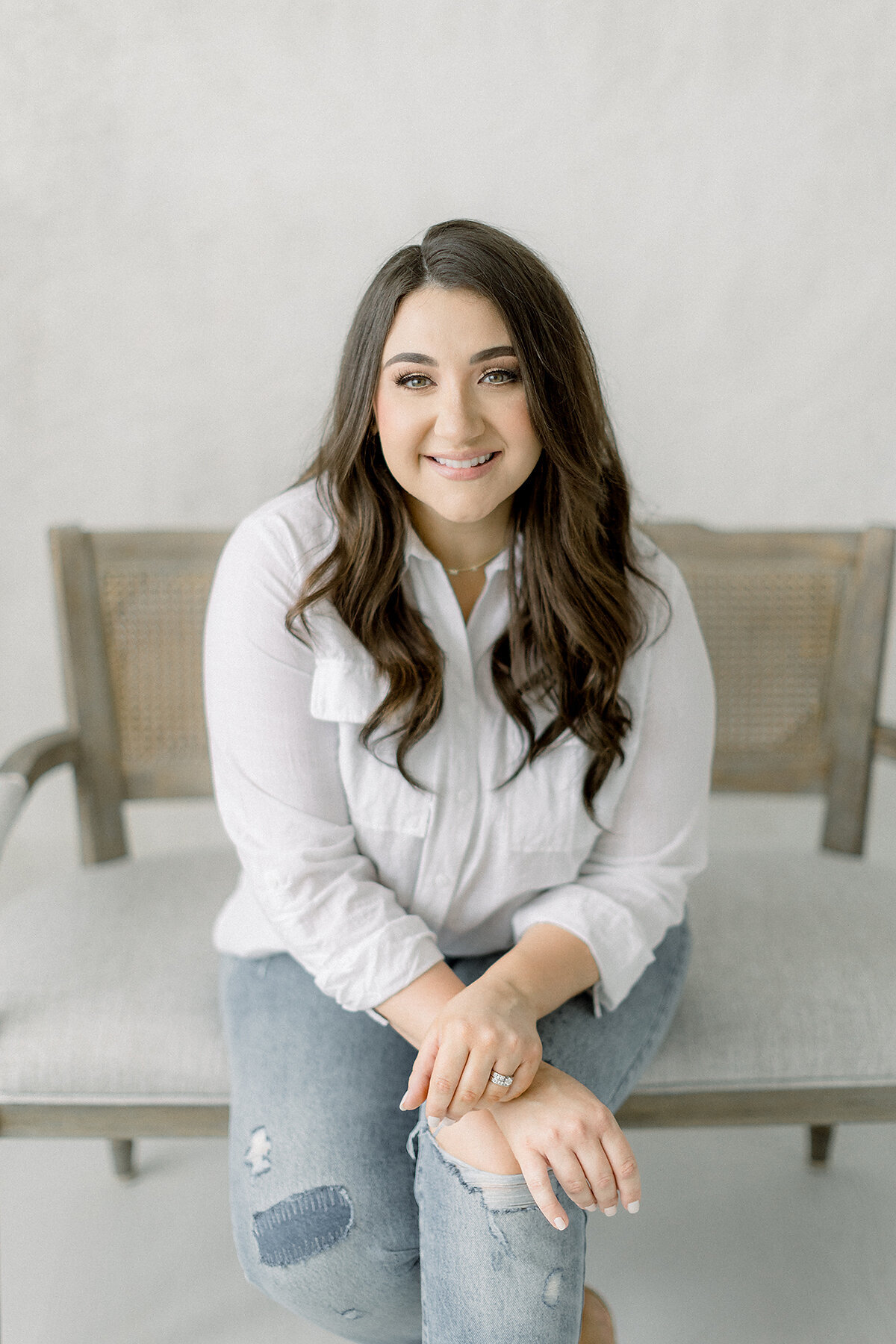 A light filled professional headshots of a local Dallas business owner sitting on a wooden bench that was taken in a Dallas photography studio.