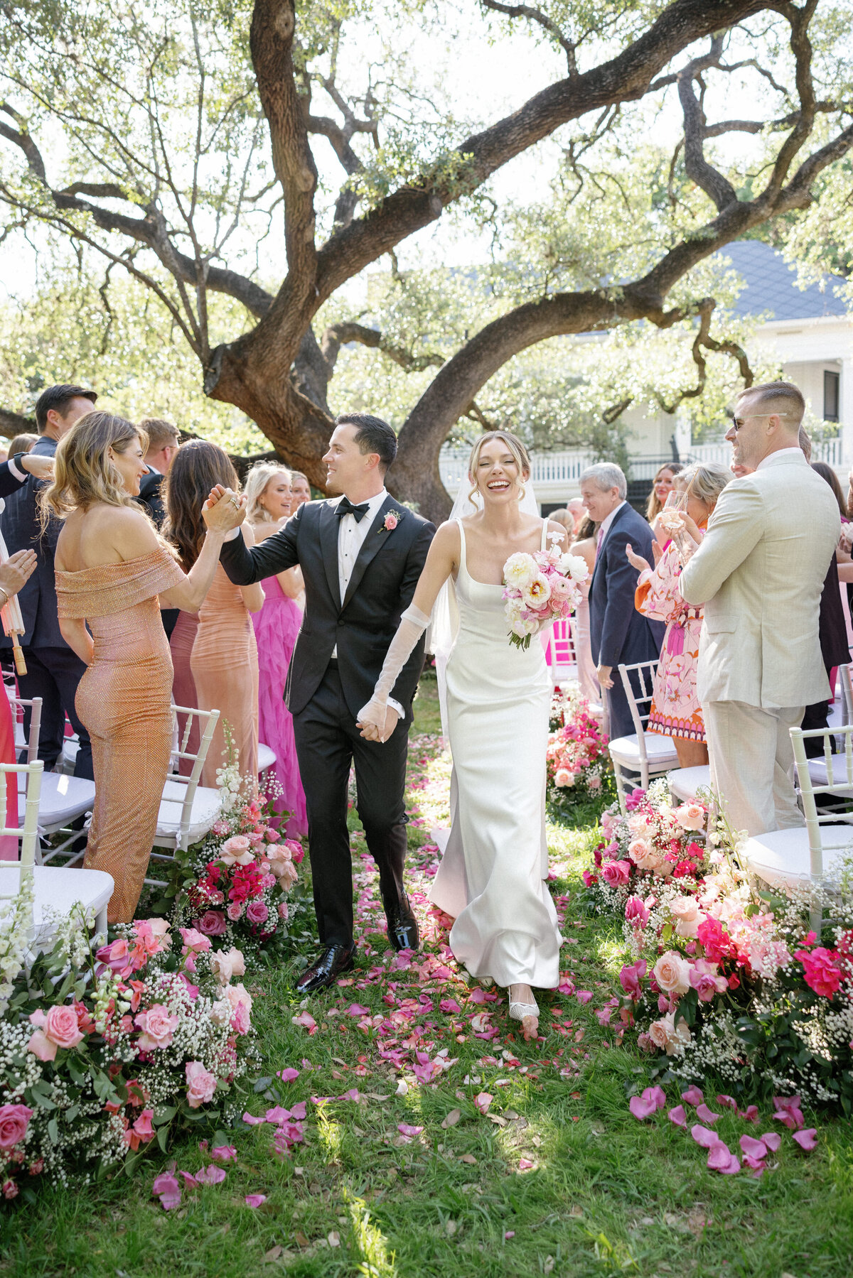 bride and groom recessing at wedding reception outdoors with pink florals