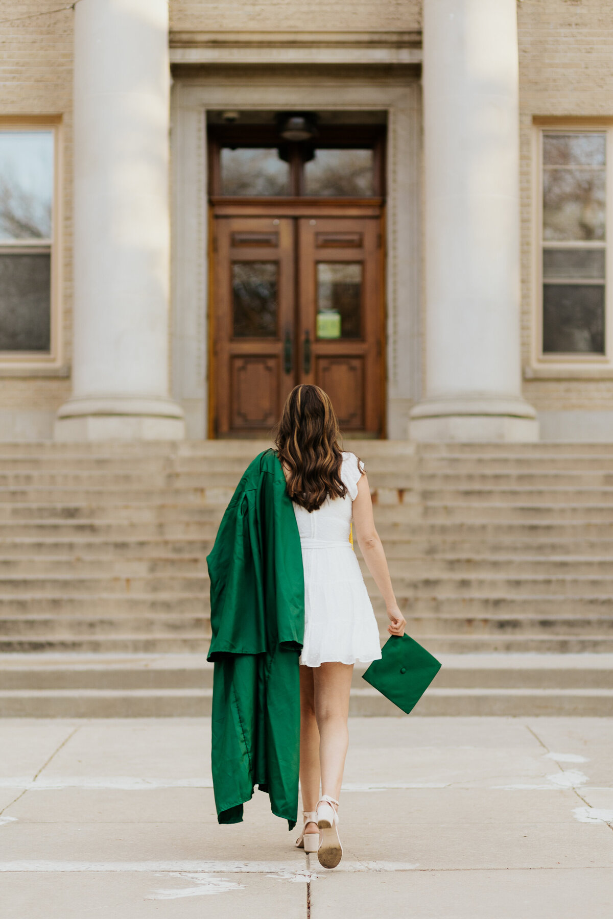 A Colorado State University graduate proudly holds her cap and gown during her grad session in Fort Collins, Colorado.