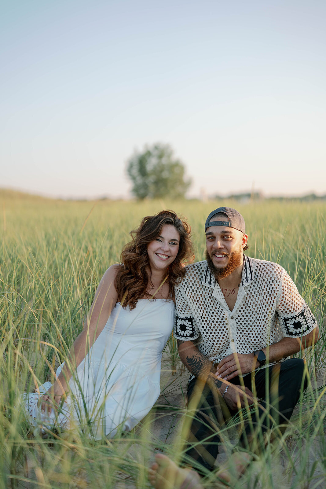 Romantic engagement portrait of couple sitting in the dunes at New Buffalo Beach, Michigan