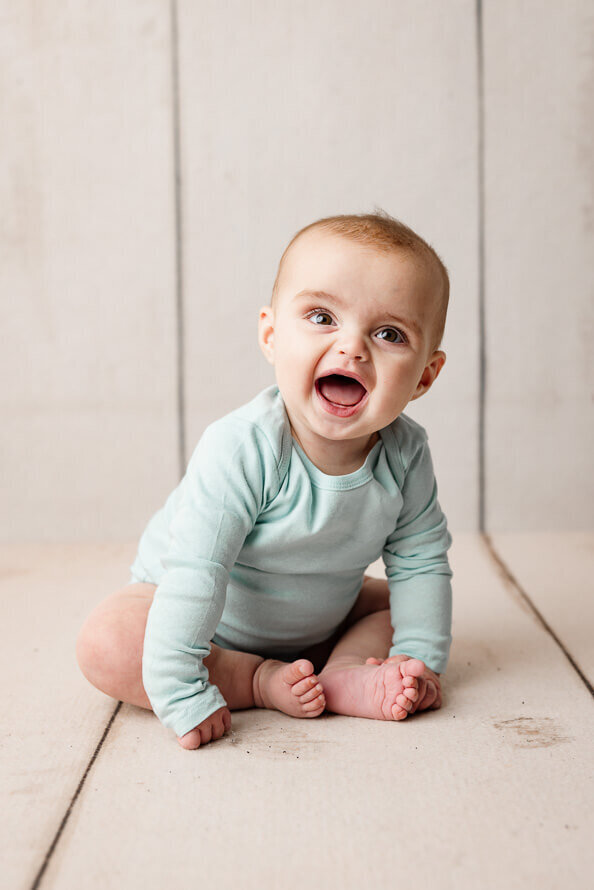 Baby laughs at photographer in the studio.