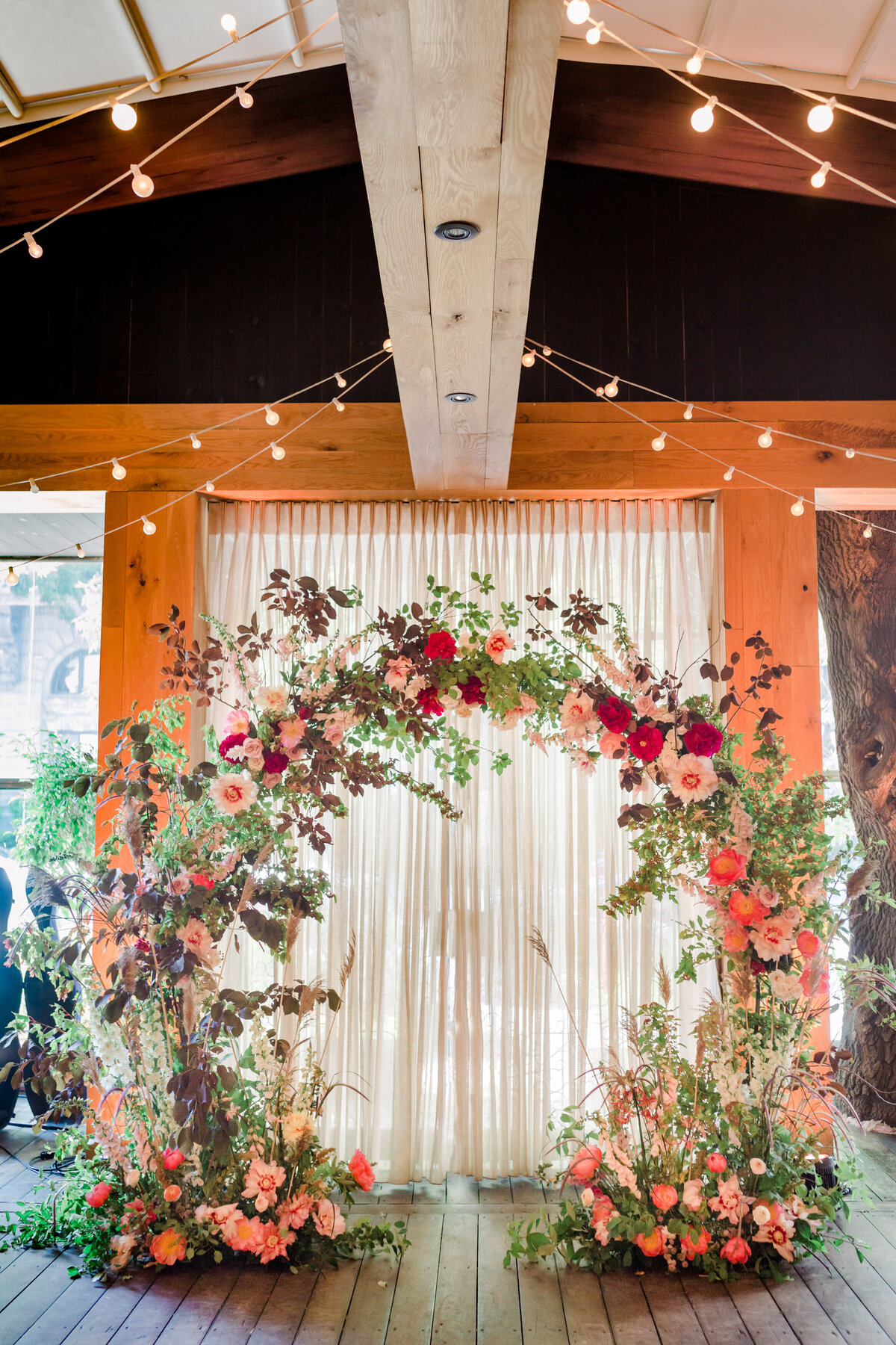 A lush arch of pink flowers and airy greenery at a wedding ceremony at Restaurant Beatrice. 