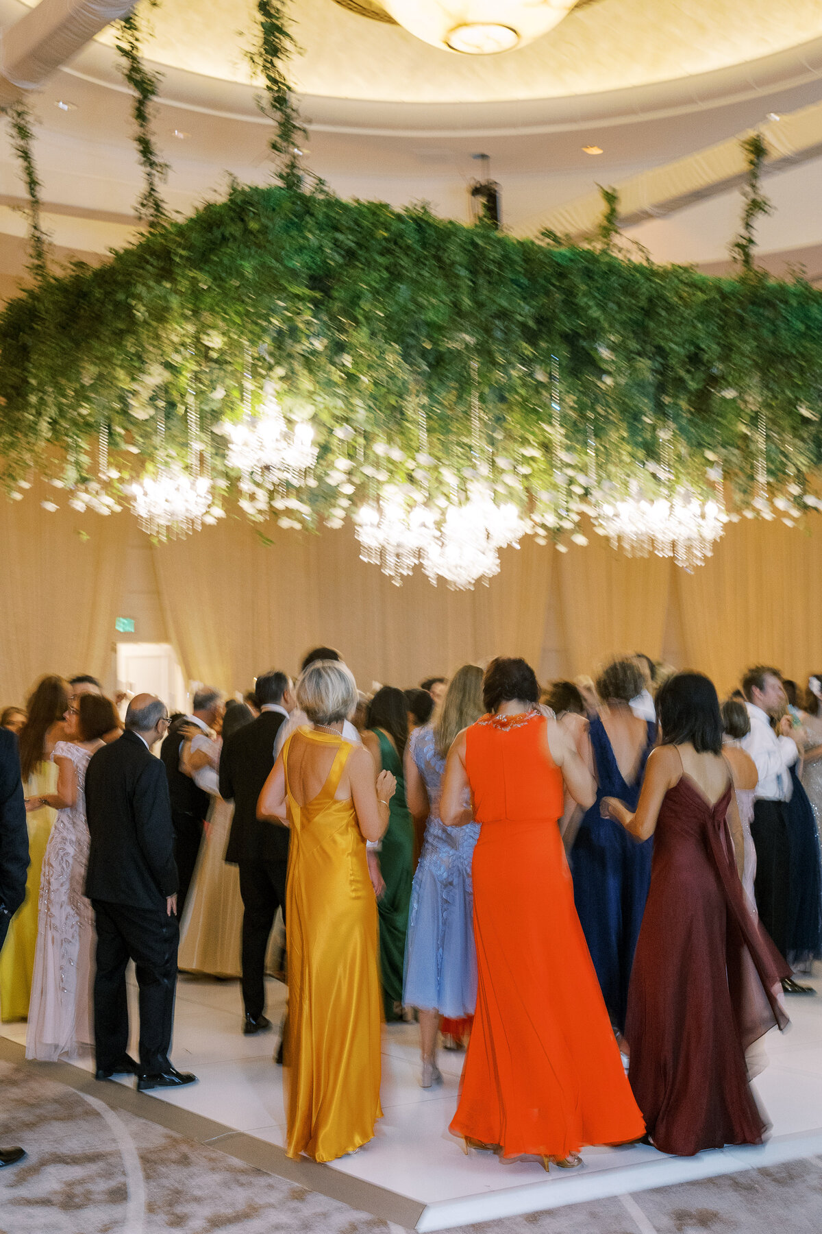 People dancing at a wedding reception under a giant floral piece