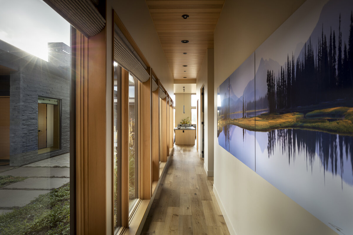 Glassy residential hallway with wood floors and art wall