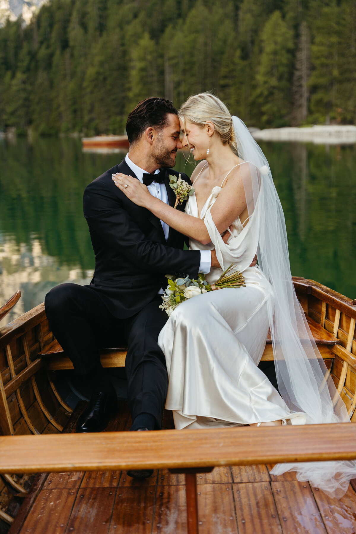 Romantic close-up of bride and groom touching foreheads on lakeside