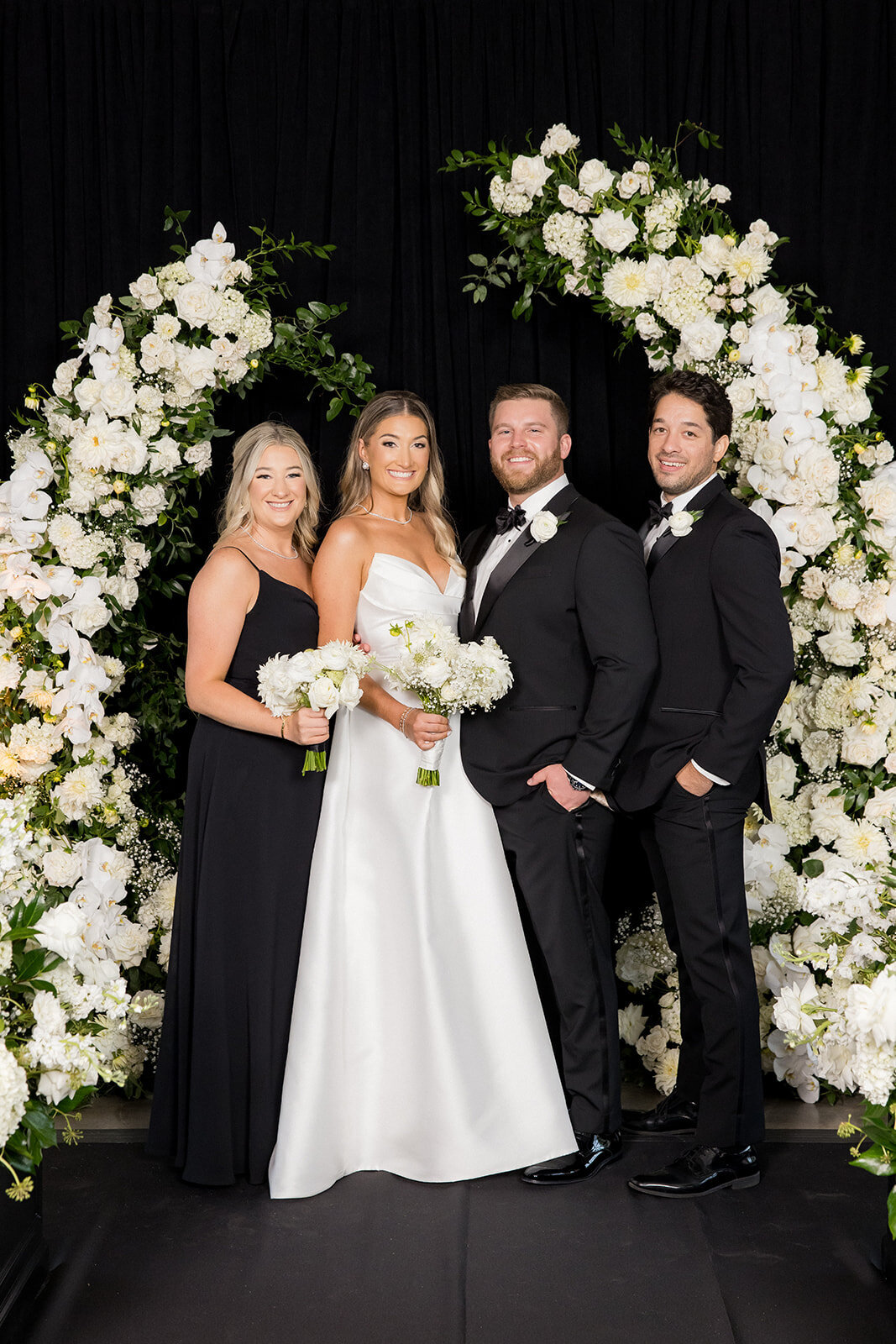 newlyweds-with-couple-arched-white-flowers-HBICWeddings