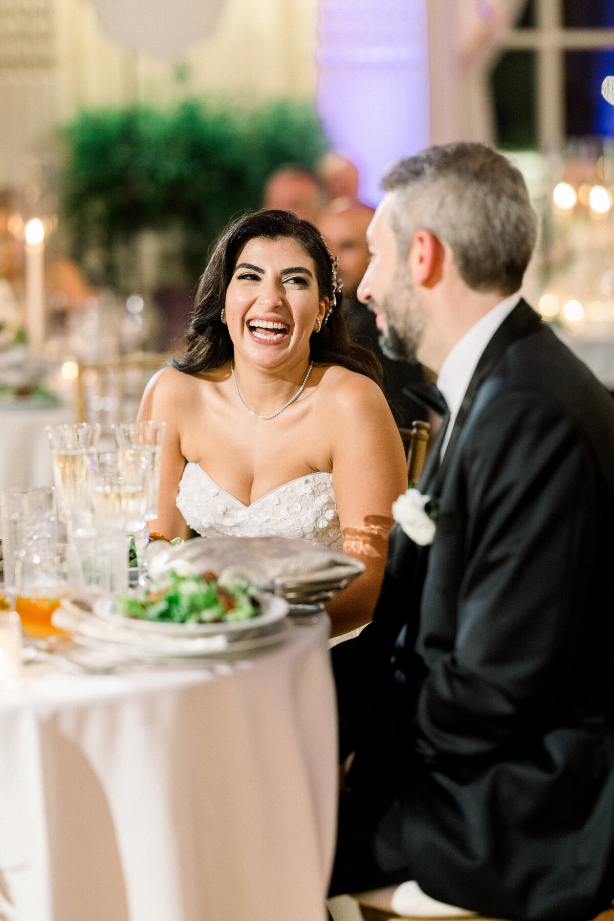 bride and groom laugh together during maid of honor speech at rosecliff mansion