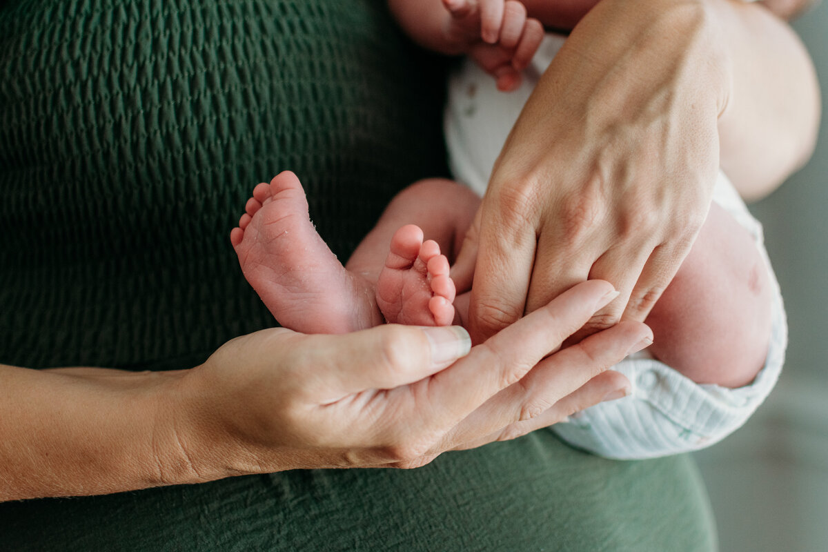 close up photo of a newborn's feet in mom's hands 