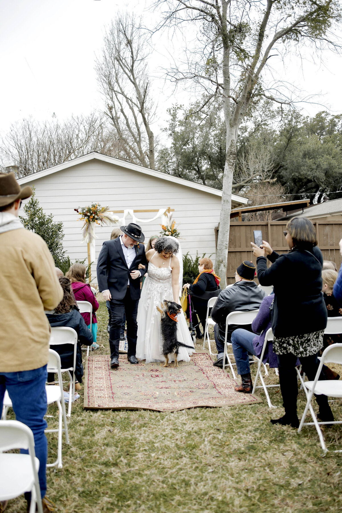 a bride and groom pet their dog at their small backyard wedding