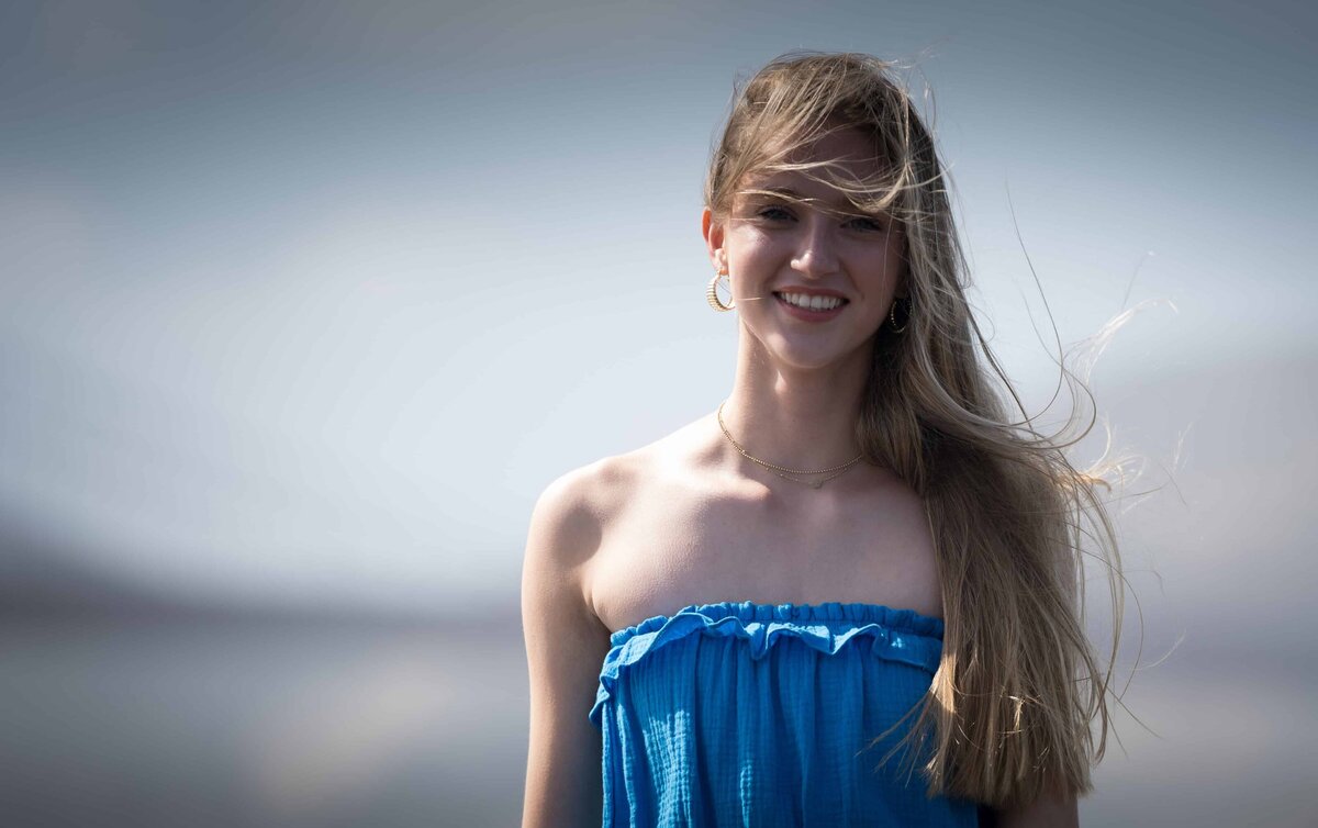 Young woman smiling in a short dress at the beach with a blurred out background