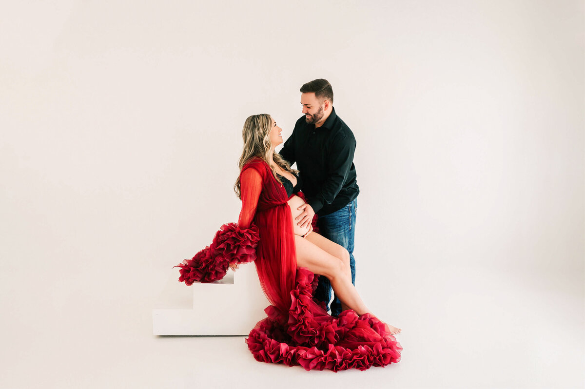 maternity photo of pregnant couple looking at each other in studio