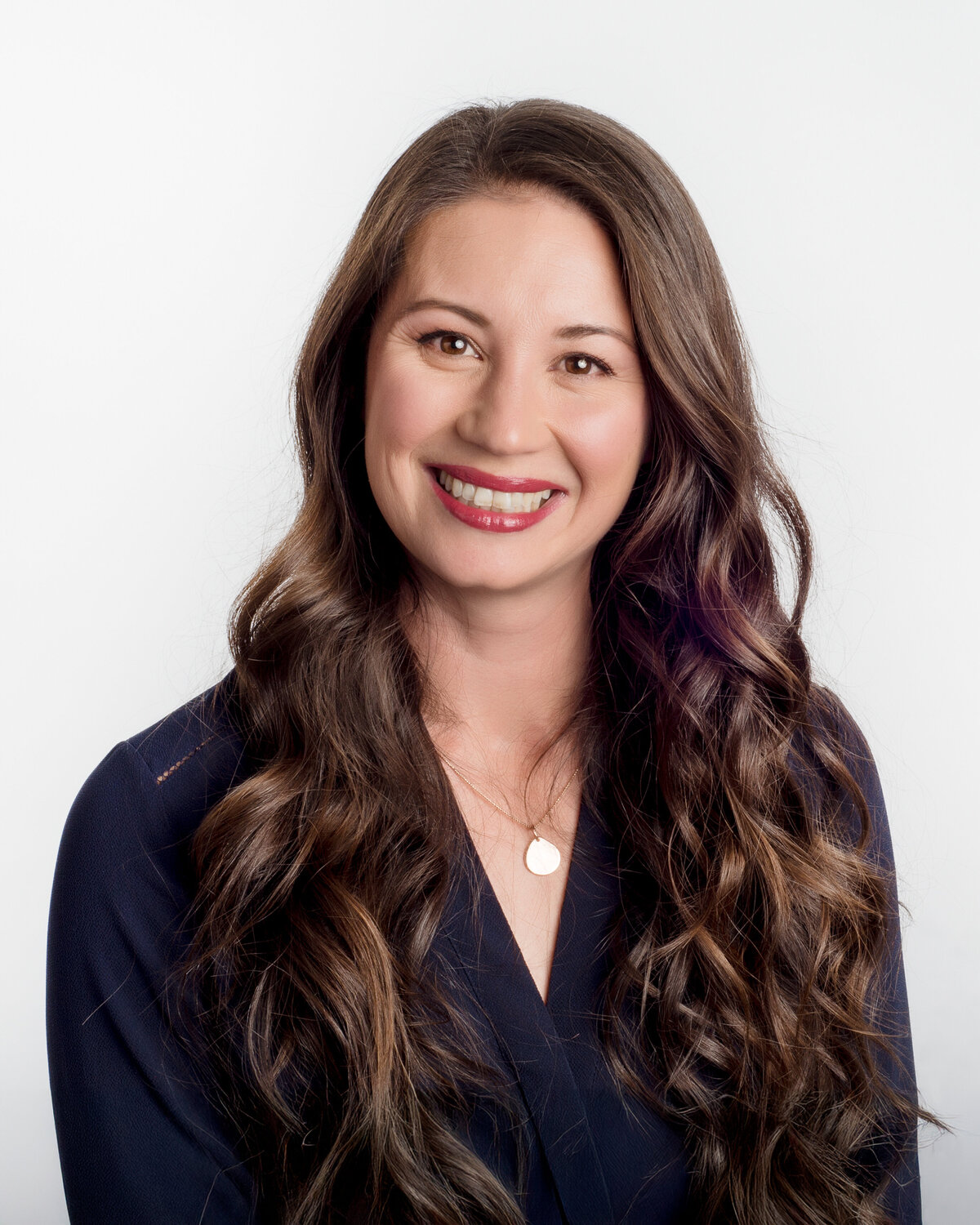 Headshot-of-woman-with-long-curly-hair-and-navy-shirt