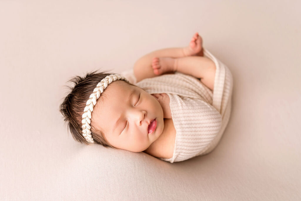 Connecticut newborn photographer specializes in classic posed portraits featuring baby girl in cream wrap with braided headband