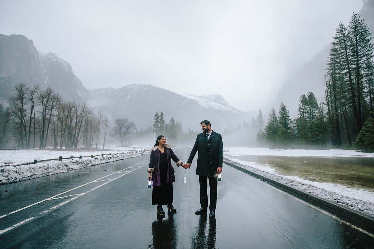 A bride and groom stand in the street in Yosemite Valley during their winter elopement.