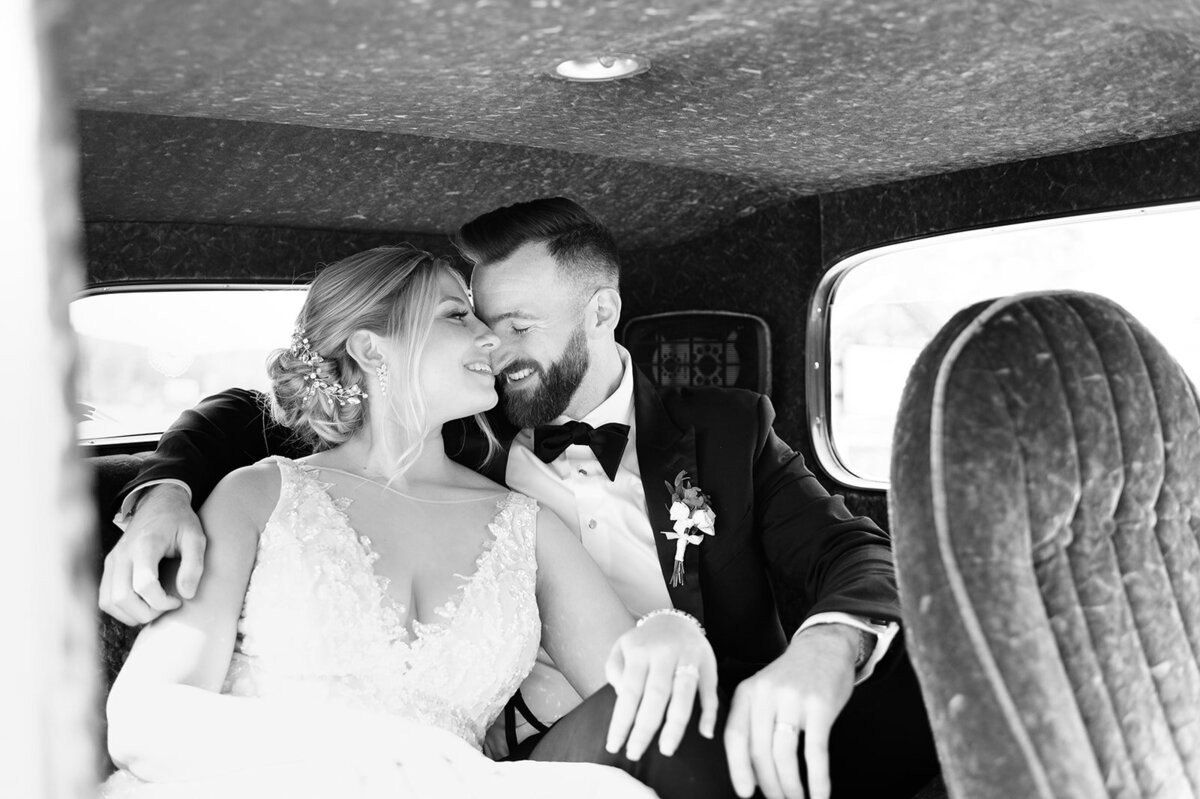 Beautiful couple canoodling in a vintage car's back seat in downtown Saranac Lake