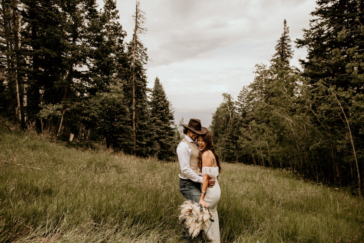newlyweds holding each other in a field of grass and the Sandia Mountain Peak in Albuquerque