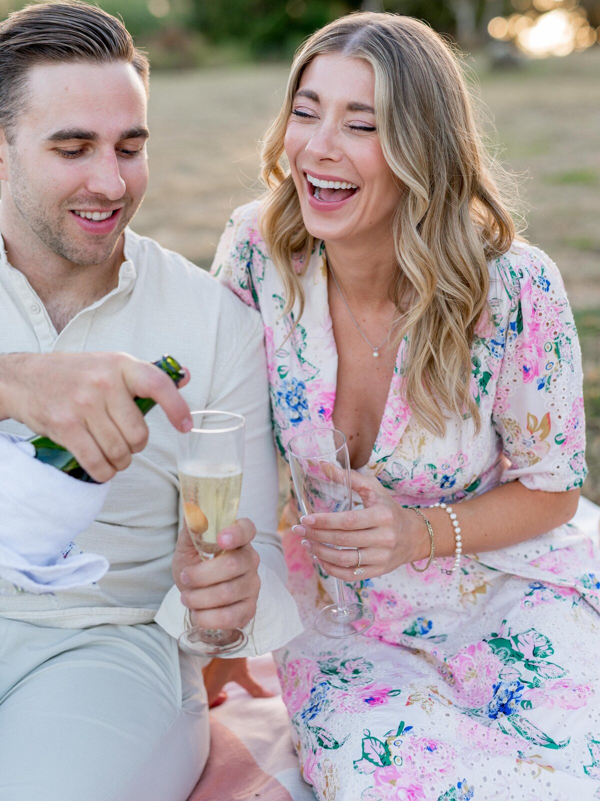Close-up of couple pouring champagne during picnic