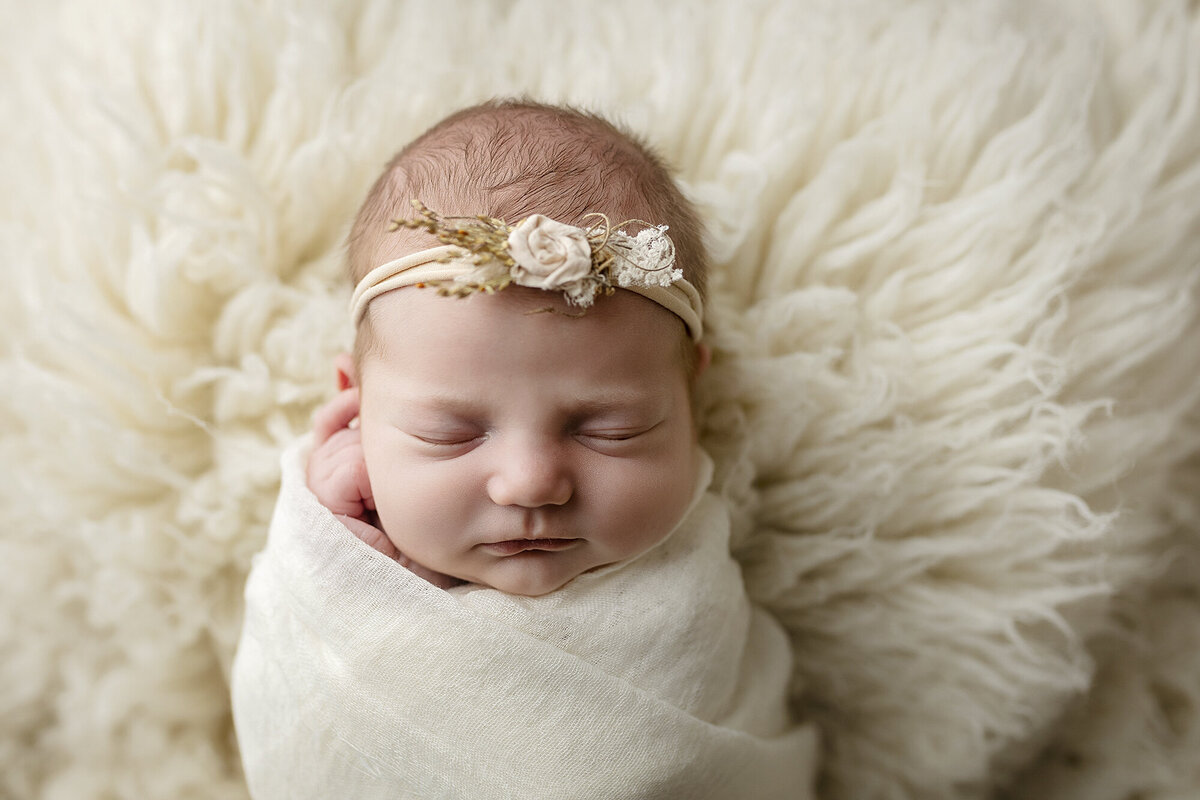 Wrapped baby girl wearing a flower detail headband.