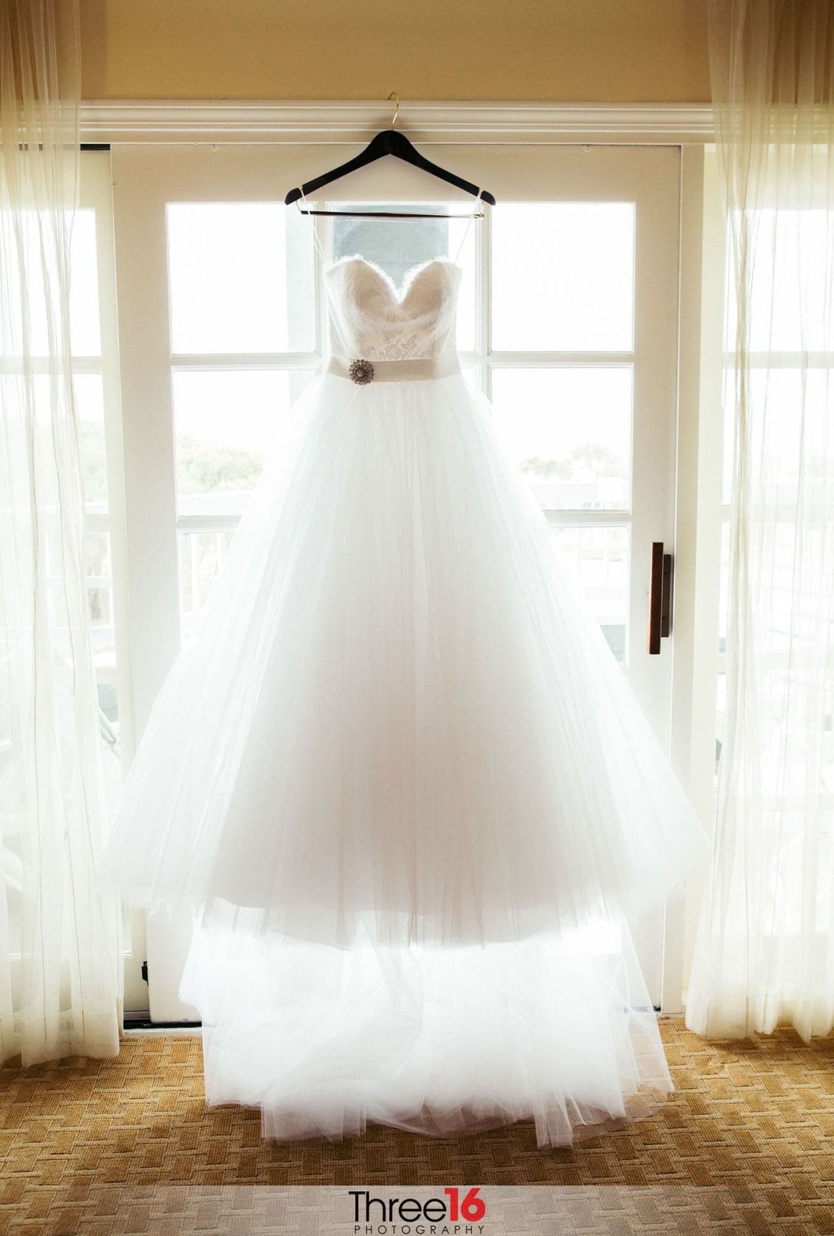 Bride's wedding dress hangs on a valance in full display