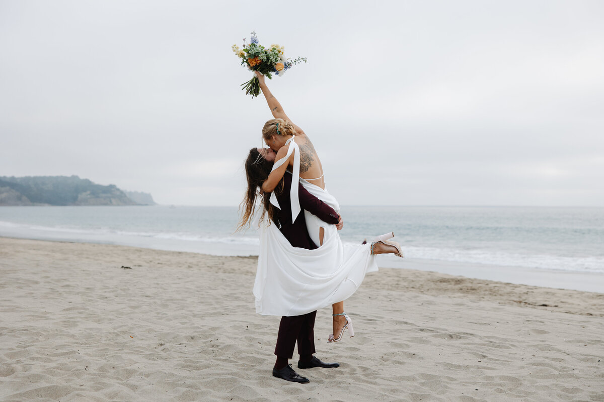 groom lifting bride while holding bouquet