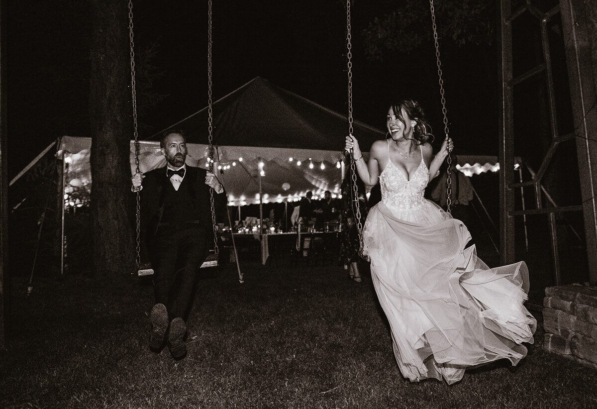 black and white photo of wedding couple on a giant outdoor swing during reception
