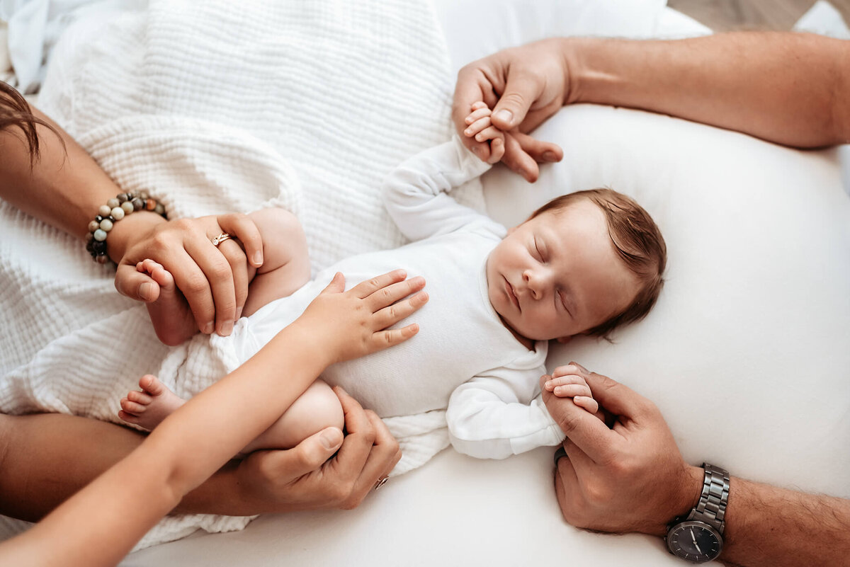 newborn boy with family's hands on him