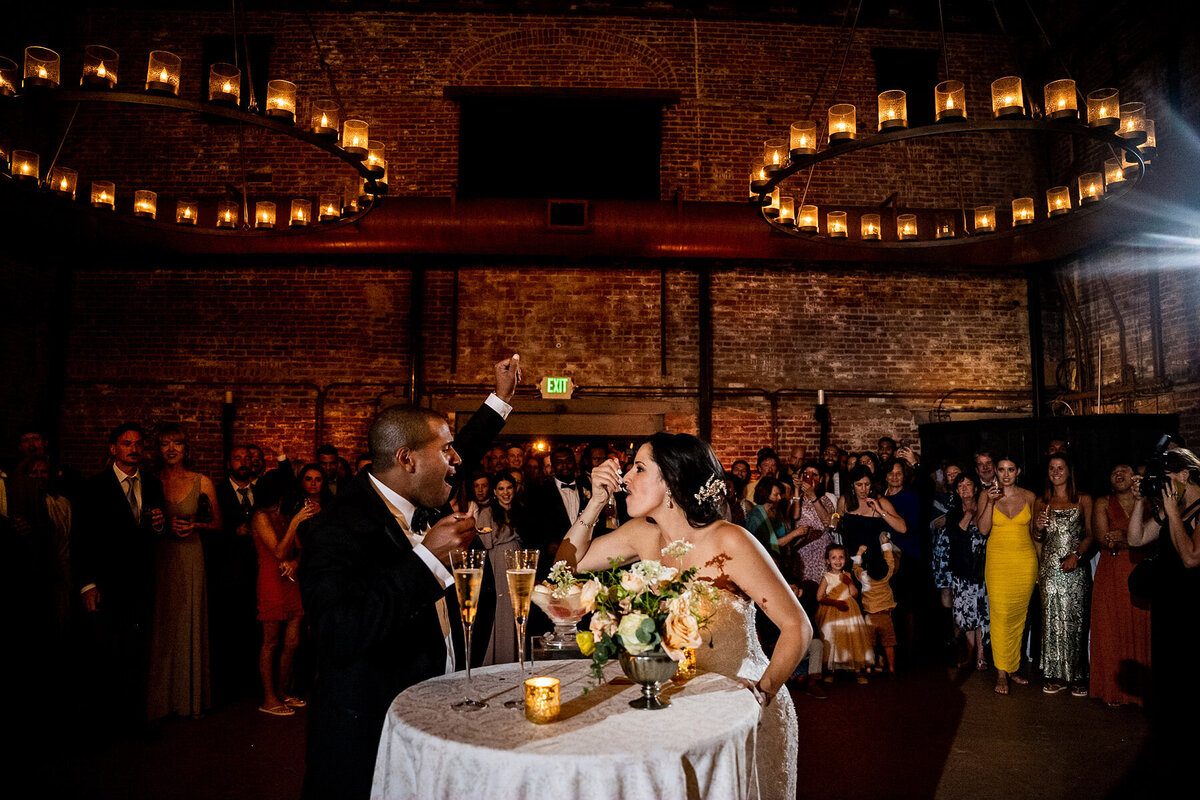 San Francisco Bay Area wedding photographer documents romantic bride and groom kiss at sweetheart table with dramatic stone architecture and circular lighting at Estate Yountville in Napa Valley