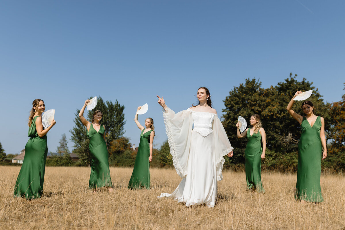 Bride with bridesmaids in green dresses at marquee wedding in Wiltshire, editorial-inspired group portrait by The Falkenburgs Studio