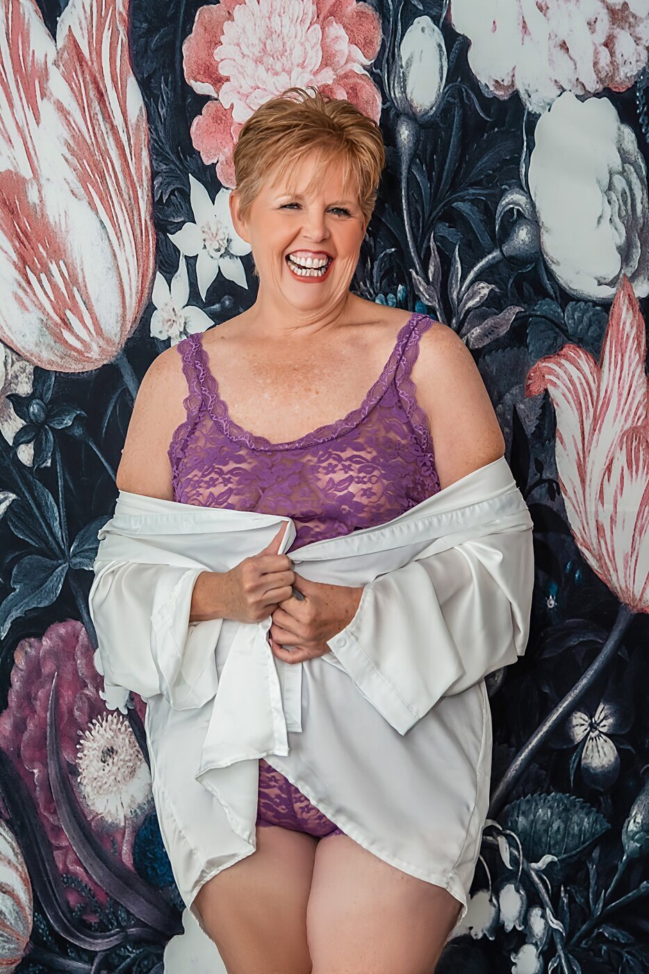A older woman in purple lingerie poses during her boudoir session.
