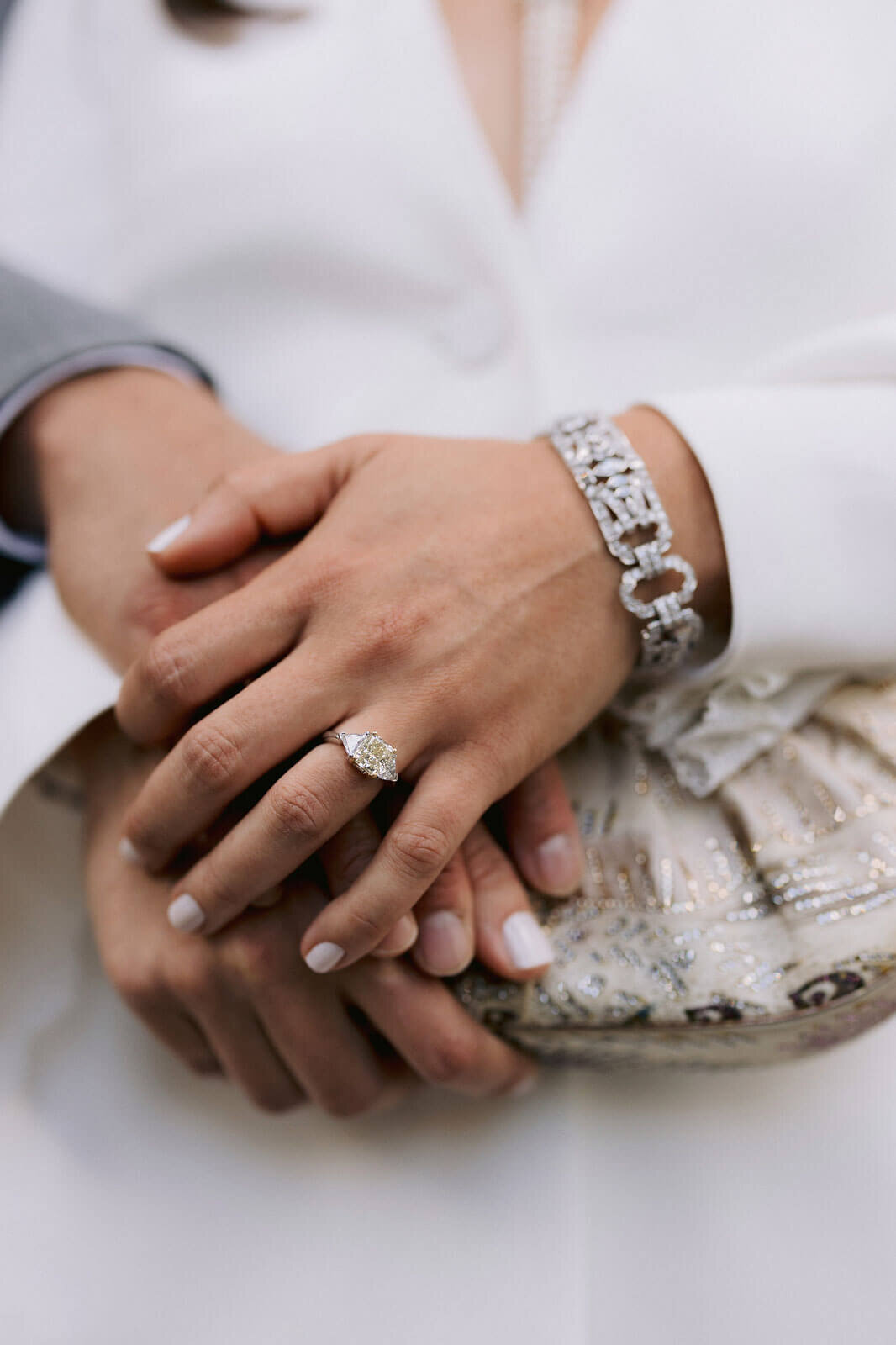 The bride and groom's hands are stacked together inside the NY City Hall. Image by Jenny Fu Studio