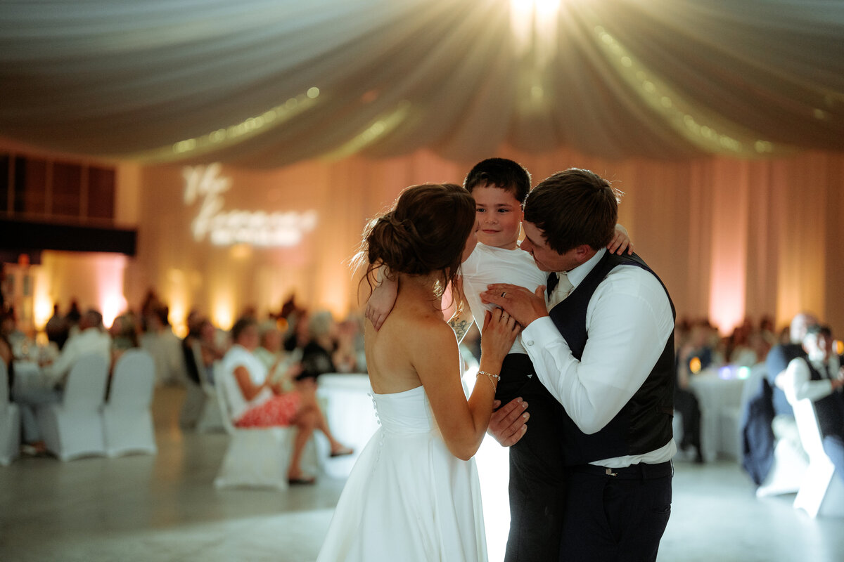 Bride and groom share first dance holding their child at a Virginia Minnesota wedding reception.