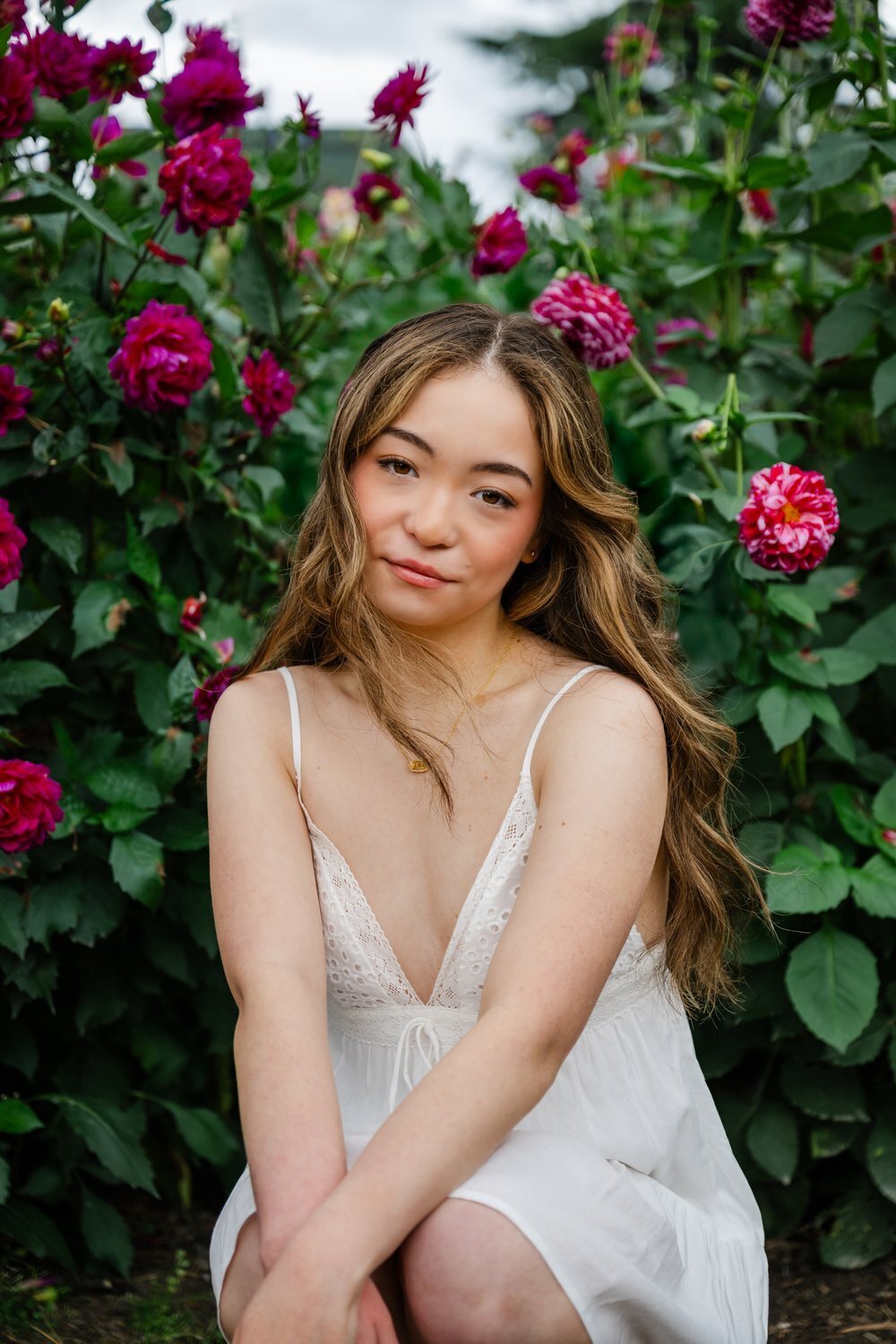 high school senior in white dress poses in bellevue dahlia garden