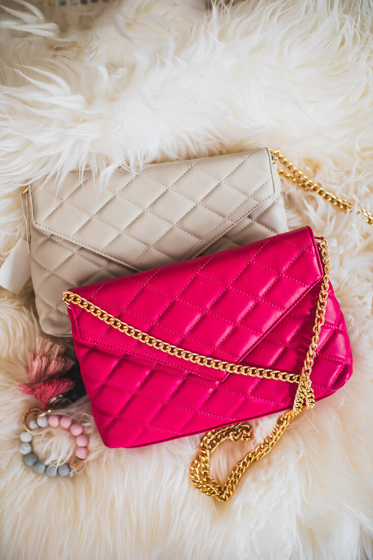 Two quilted handbags with chain straps displayed on what appears to be a furry white surface. One bag is cream/beige colored and the other is bright pink, both featuring similar diamond quilted patterns and gold chains.