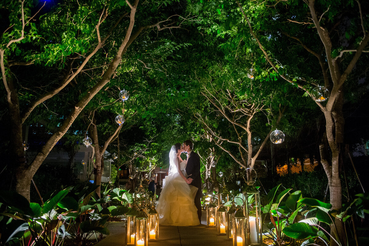 Romantic Miami garden wedding at night with bride and groom kissing under a canopy of trees, captured by Rodrigo Varela Photography