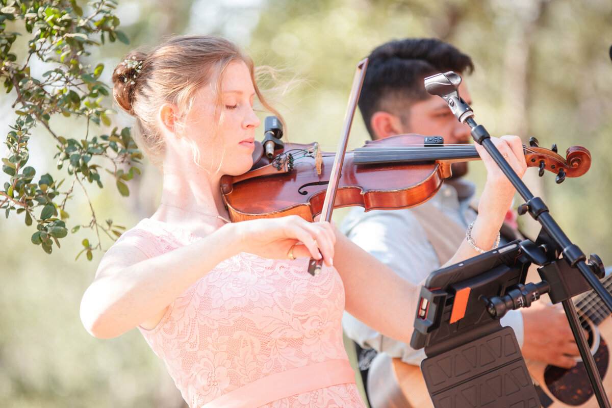 woman in peach dress and bun plays violin at Boerne wedding