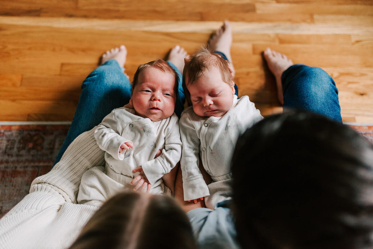 one twin looking at dad while the other one sleeps