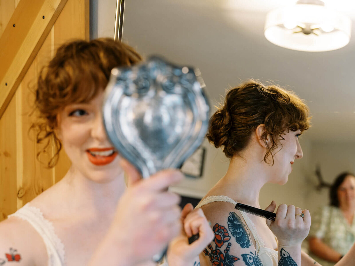 A woman holds up a mirror to look at her hair. 