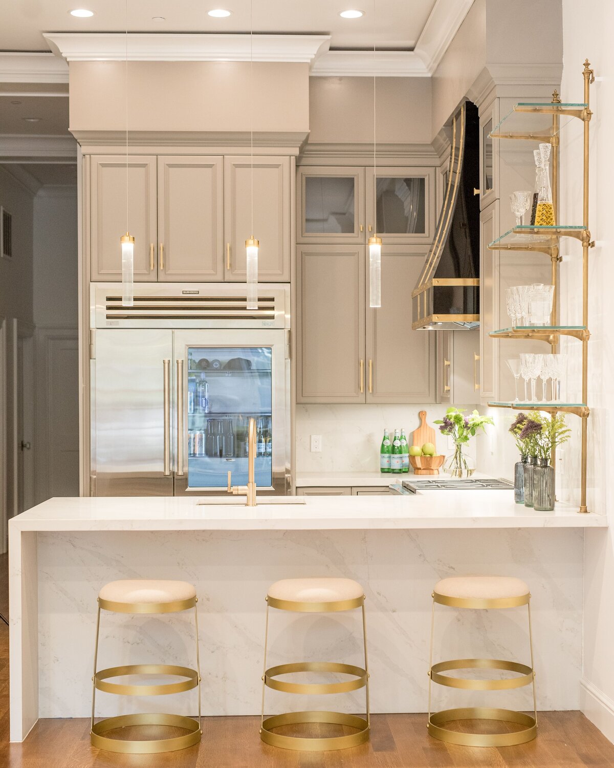 Luxury kitchen on Comm Ave featuring gold bar stools, a waterfall island, and modern finishes