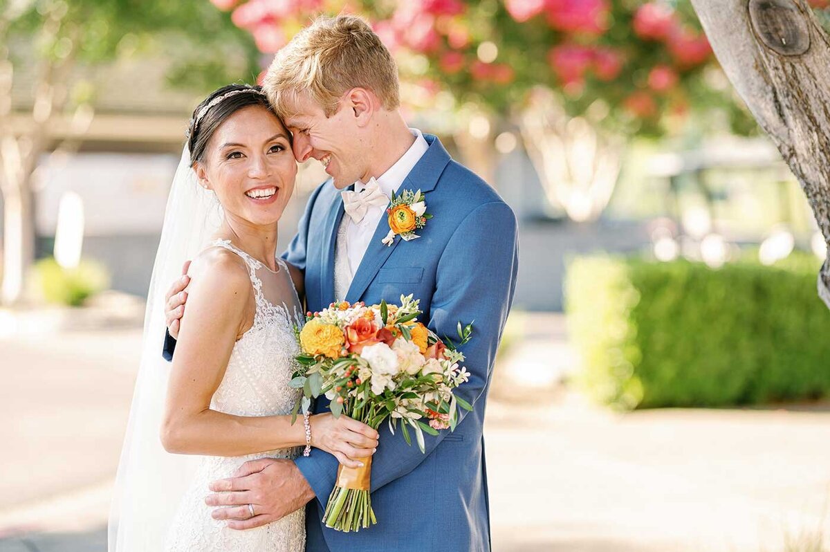 Light and bright photo of bride and groom with floral bouquet