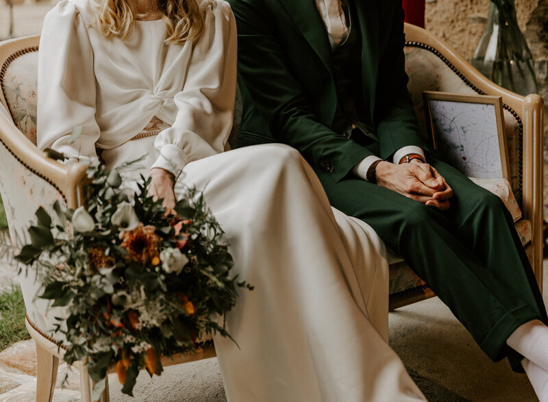 Mariés assis dans un canapé vintage lors de la cérémonie laïque immortalisée par Laura, photographe mariage en vendée.