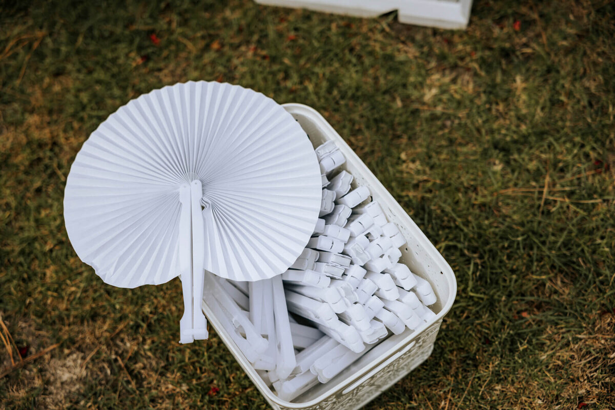 A white box filled with lots of white hand fans