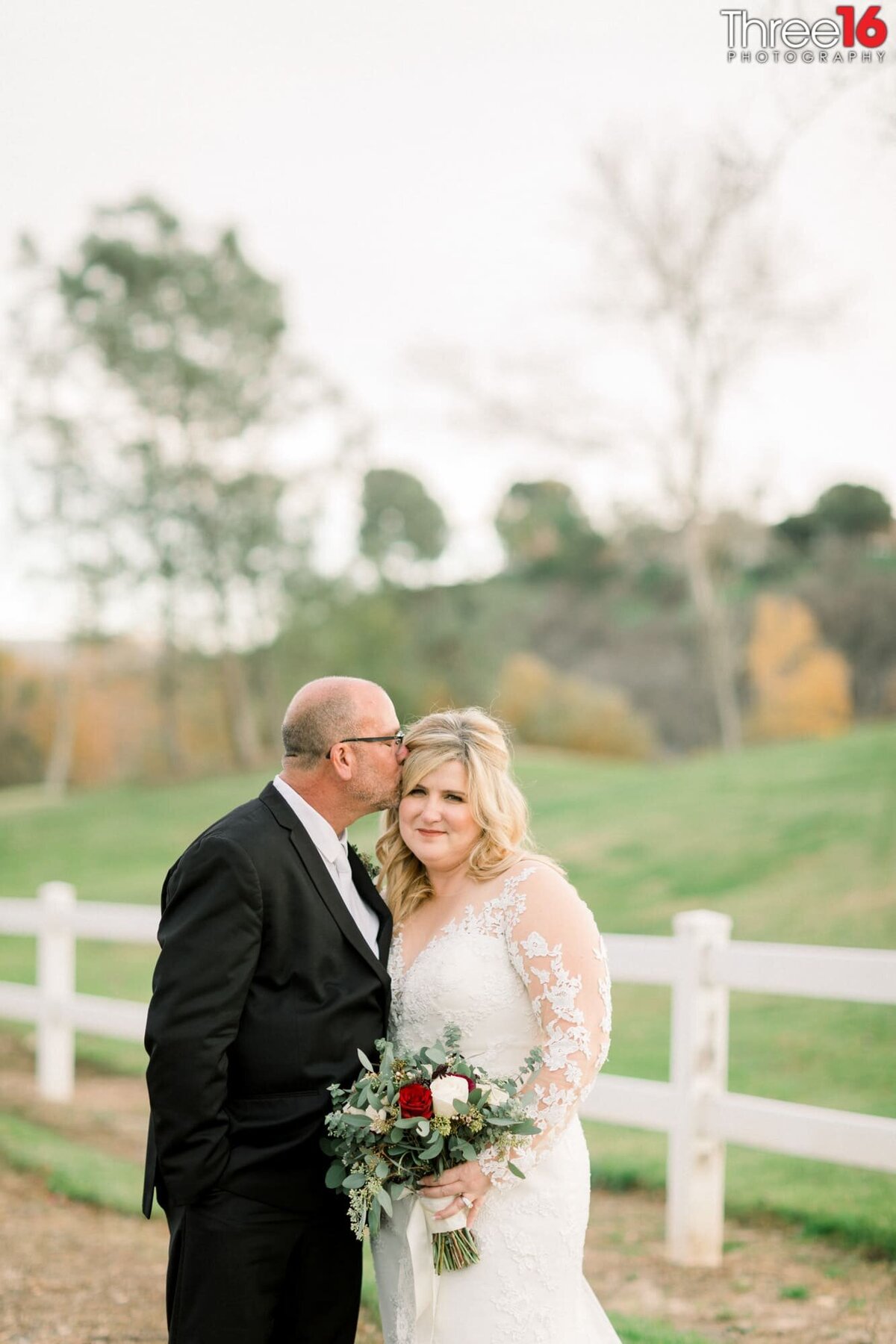 Groom kisses his Bride on the side of her head