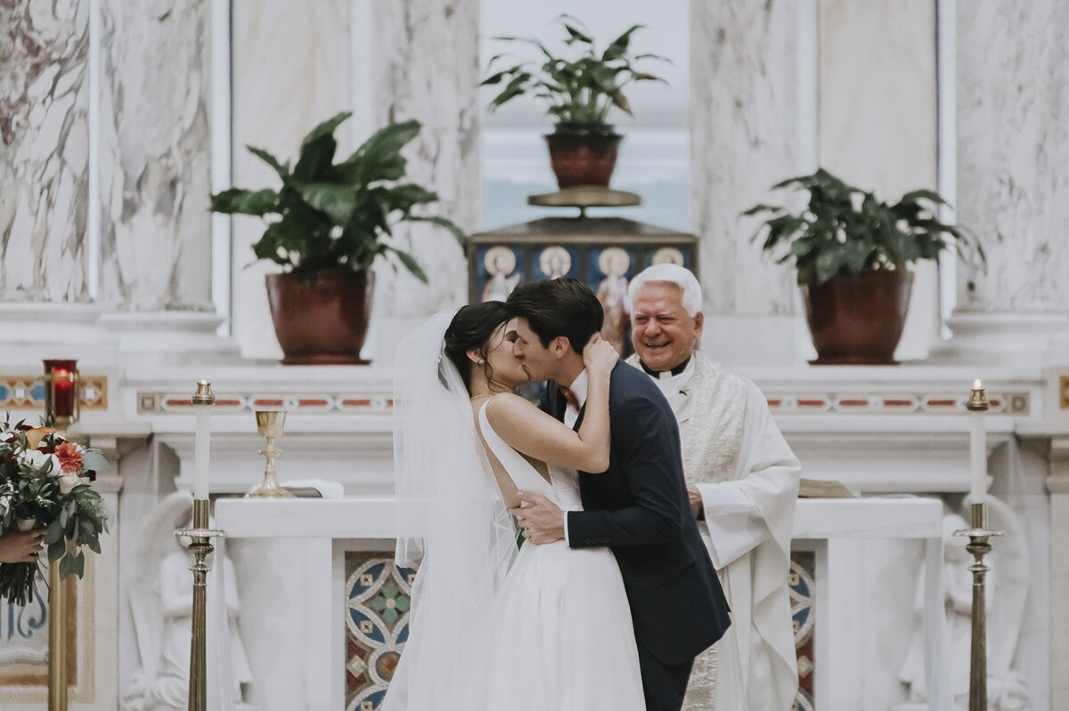 Catholic bride and groom kissing at the altar
