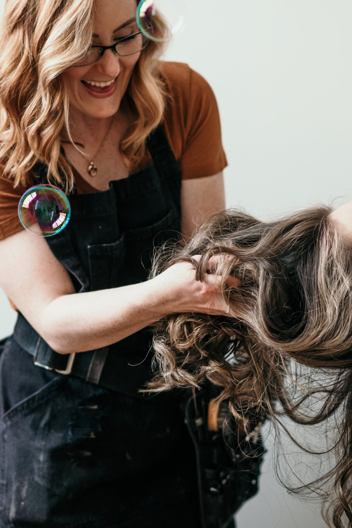 hairstylist holding client's hair laughing