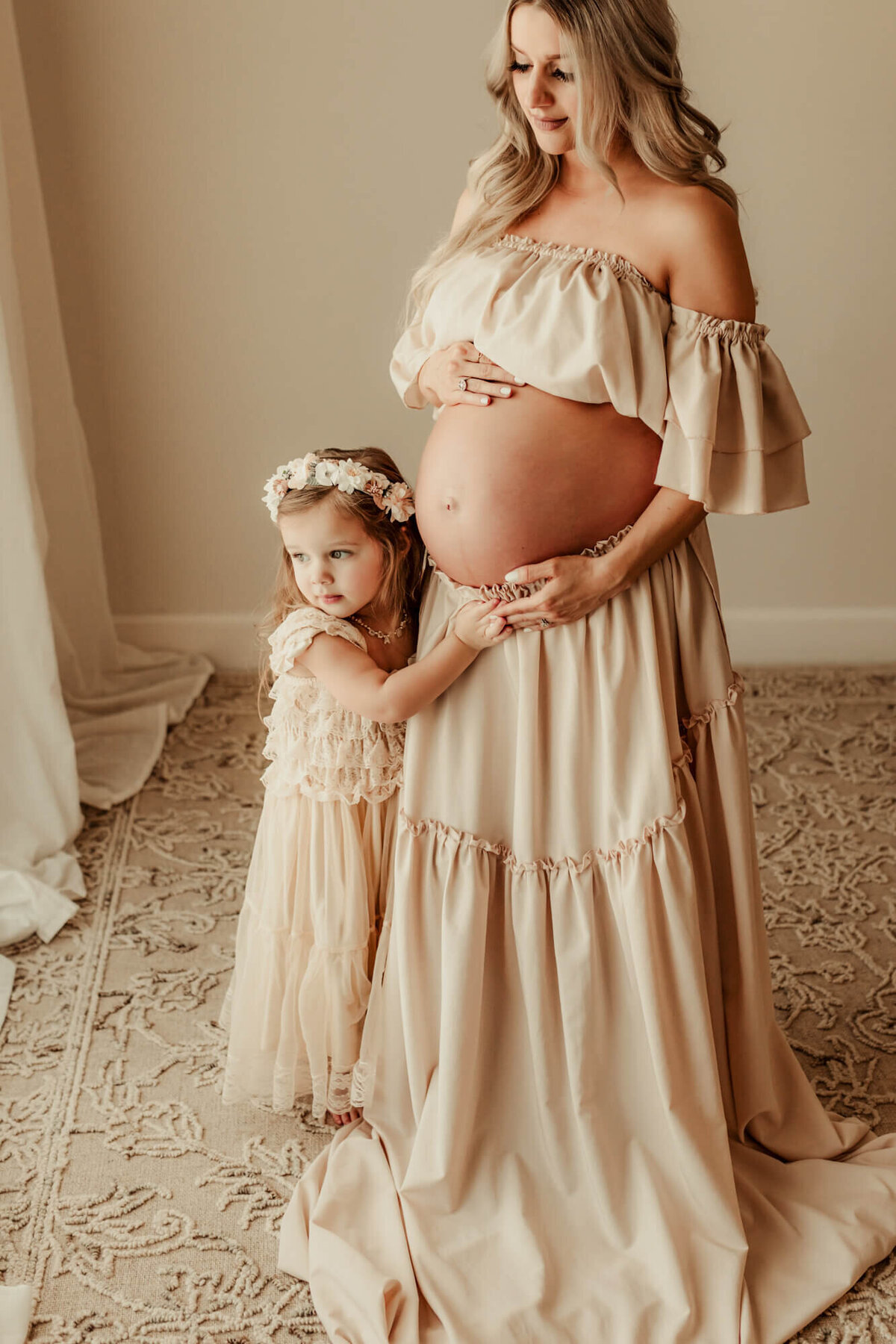 Little girl stands next to her expecting mother's belly, lifestyle maternity photo session OKC.