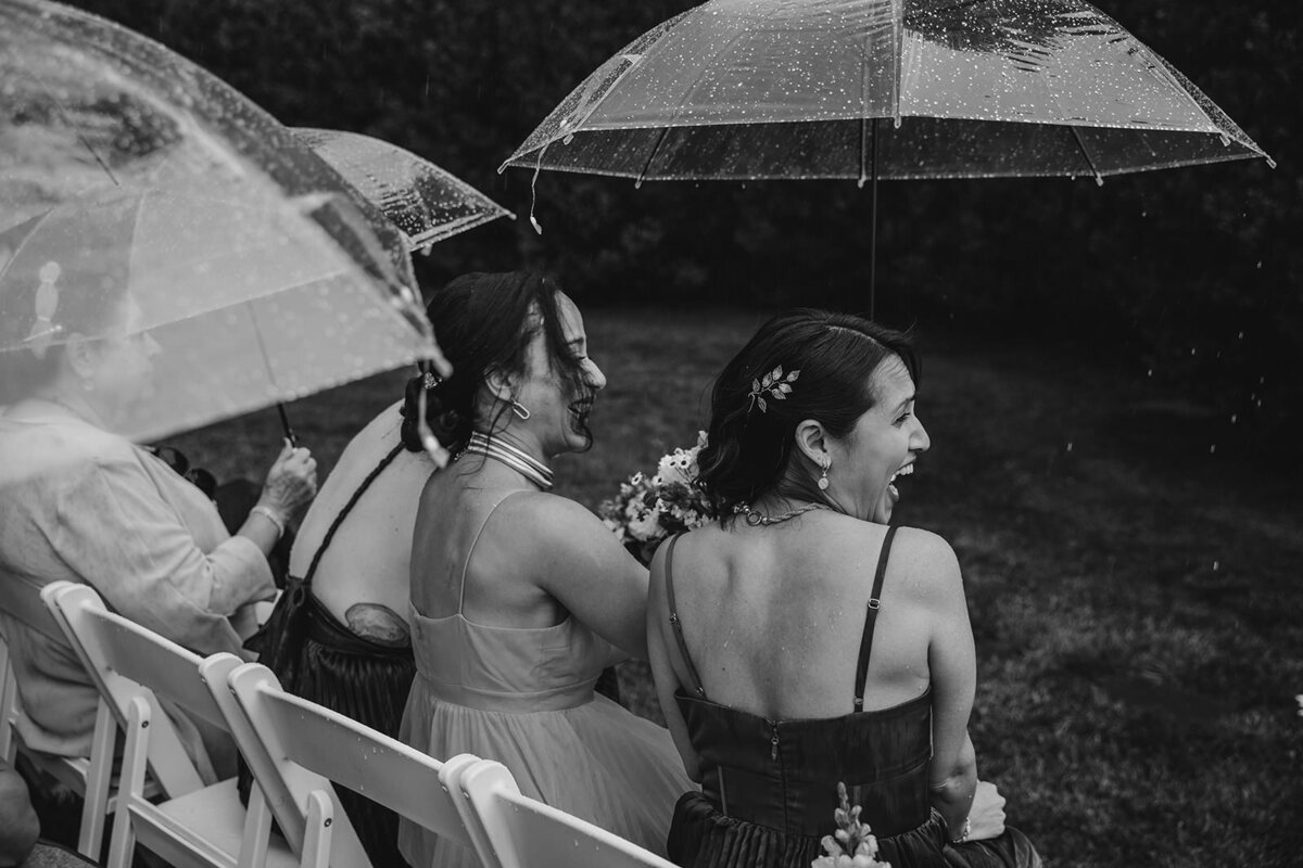 Wedding guests sitting down with clear umbrellas over them 
