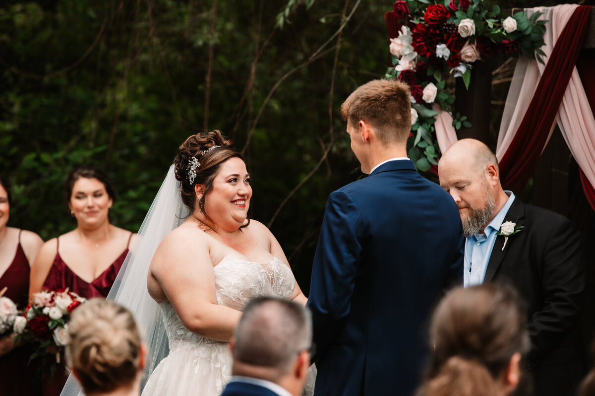 A bride smiles big during her ceremony at the altar